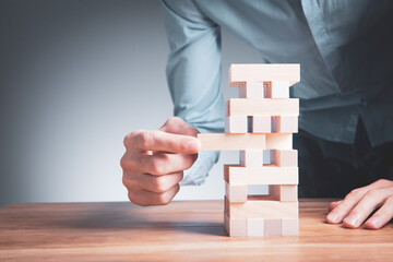 Closeup of a businessman making a structure with wooden cubes. Building a business concept.