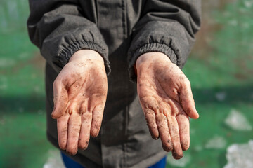 Mud-stained hands of a child close-up. Pampering, game or knowledge of nature world and environment