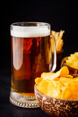 mug of beer and a set of dry fish snacks on a dark background