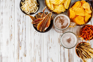 mug of beer and a set of dry fish snacks on a white wooden rustic background
