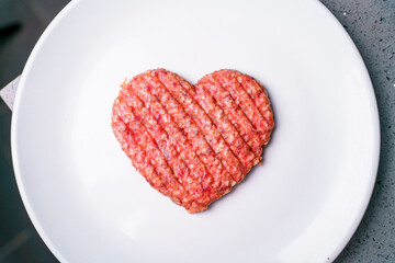 Obraz na płótnie Canvas Meat cutlet in the shape of a heart. Dinner for lovers on February 14th. Meat love. Valentine's Day. Mince heart