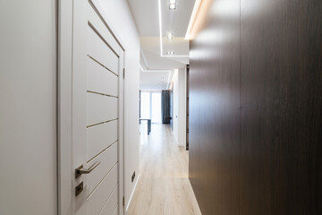 large corridor with white doors dark and light wall