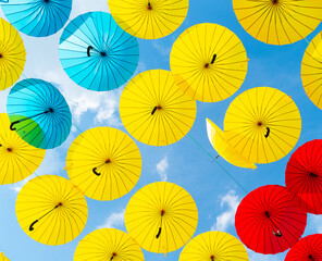 Multicolored umbrellas hanging blue sky background. Street decoration