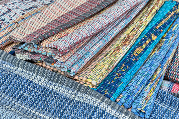 Homemade colourful woven rugs made of fabric ribbons stacked. Close-up.