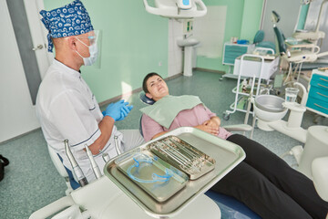 Selective focus dental equipment for dentist and blurry dentist examining patient on chair at dental department.