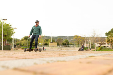 Young man using a electric skateboard on a square. Urban scene. Mobility.  