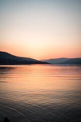 A landscape photograph looking across the waters of Loch Lomond at sunset.
