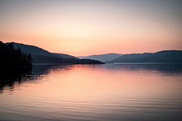Fototapeta na wymiar A landscape photograph looking across the waters of Loch Lomond in Scotland at sunset.