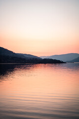 A landscape photograph looking across the waters of Loch Lomond in Scotland at sunset.