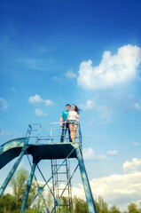 A man and a woman - a couple in love on a metal structure against a blue sky