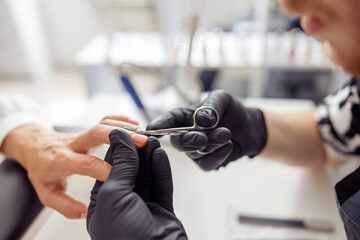 Manicure specialist providing nail service for client in salon