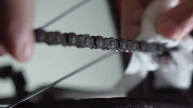 Cleaning bicycle chain with cloth. Regular, common bike maintenance at home, close up, details. Selective focus