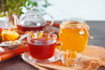 Cup of herbal tea with flowers, honey in jar, teapot and and various dried herbs on the tray.