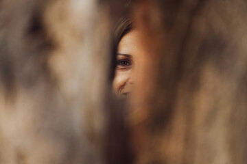 the face of a smiling woman seen through the hollow of a tree. detail.