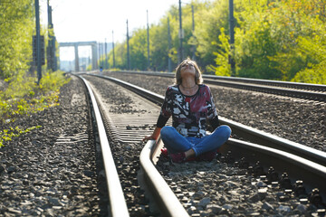 smiling woman posing on the railway lines on a sunny day.