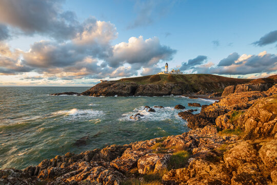 Killantringan Lighthouse on Black Head and rocky coastline at sunset, Portpatrick, Dumfries and Galloway, Scotland