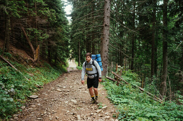 Fototapeta na wymiar male hiker in casual clothes with a backpack on his back walks on a trail in the mountains during a hike.