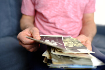 close-up of old male hands holding retro family photos of 1960-1965, vintage monochrome photographs...
