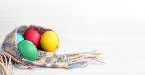 multi-colored chicken eggs in a knitted scarf on a light table. warm spring holiday easter