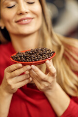 Close up of a woman smelling coffee beans.