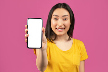 Cool offer. Portrait of happy asian woman holding cellphone with blank screen in hand, showing...