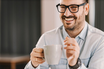 A happy man holding mug with coffee or tea and smiling.