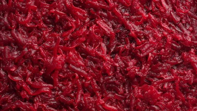 Background and texture of raw fresh juicy grated red beetroot vegetable, close up, top view, rotates
