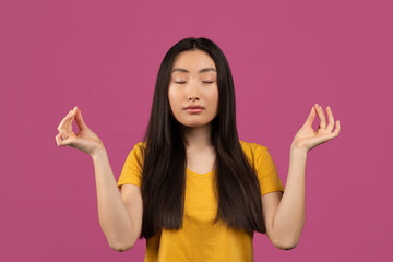 Serene young asian woman with closed eyes meditating, enjoying silence and relaxation over violet...