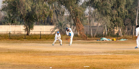 young boys playing cricket in the local city playground 