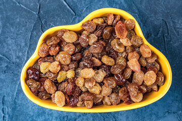 delicious sweet yellow raisins in a yellow bowl on the table close-up