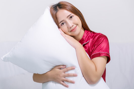 Happy woman enjoy fresh soft bedding linen and mattress in bed room modern hotel. Recommend produc for sleep. Portrait of young Asian girl wearing red pajamas.