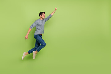 Fototapeta na wymiar Full body photo of cheerful cool positive super male flying to save the world isolated on green color background