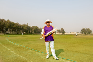 cricketer holding cricket bat in match ground