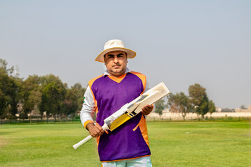 cricketer holding cricket bat in match ground