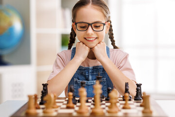 Happy girl playing chess at school - obrazy, fototapety, plakaty