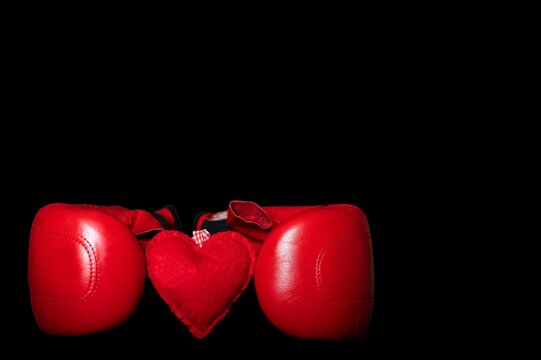 On Valentine's Day, boxing red gloves hold a heart made of red fabric as a symbol of the holiday.