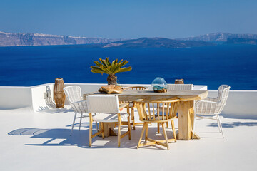 A sun terrace with a wooden table and chairs in Thira, Santorini island, Greece. Beautiful rest...