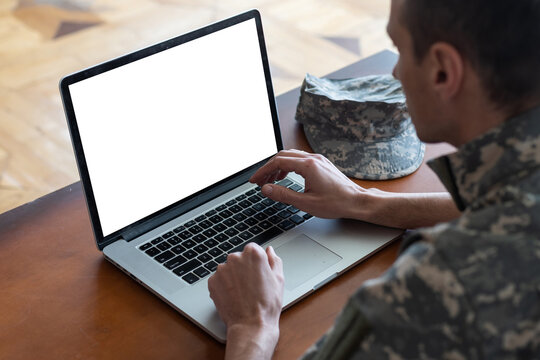 Army. Young soldier working with a laptop computer with blank screen on black background.