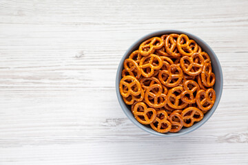 Crispy Salty Baked Pretzels in a Bowl on a white wooden background, top view. Flat lay, overhead, from above. Copy space.