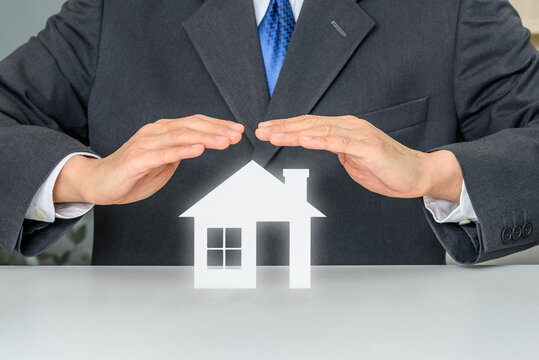 Protection from mortgage foreclosure and land contract forfeiture, business concept : Businessman protects a home or a house, depict protecting a borrower or buyer from failing to pay money to lender