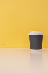 Paper coffee mugs filled with hot coffee are placed on a table in a cafe on a bright yellow blur background, there is space in the image for design and copy space for inserting text for advertising.