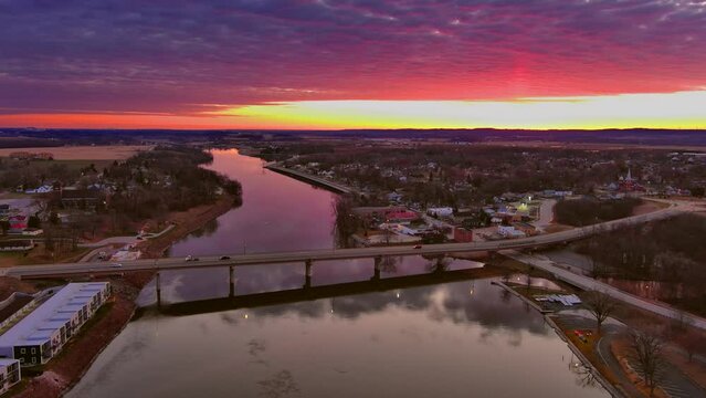 Small town America awakens and drives to work under moody red sky, aerial drone view.

