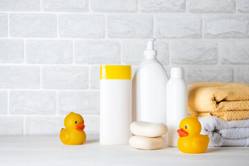 Baby bath accessories, towel, yellow rubber duck and shampoo bottles. The concept of child care.