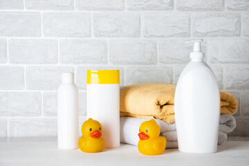 Baby bath accessories, towel, yellow rubber duck and shampoo bottles. The concept of child care.