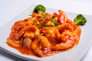 Shrimp in tomato sauce on a white square plate. Closeup. Chinese food.