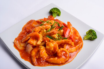 Shrimp in tomato sauce on a white square plate. Closeup. Chinese food.