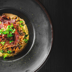 Spelt with venison jerked beef in black plate