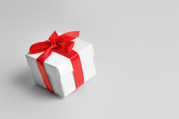 White box with a red ribbon on a white background, copy space. Greeting card concept. Gift concept. Copy space