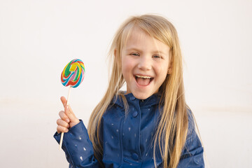 Happy smiling child with sweet lollipop having fun over white background outdoors