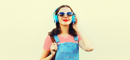 Portrait of happy smiling young woman with headphones listening to music on white background
